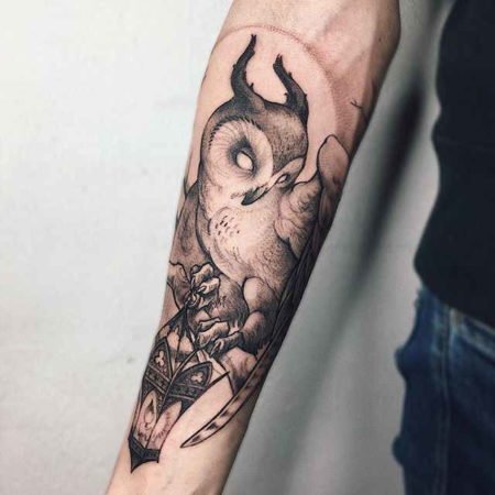 Lanterna e tatuagem de coruja no antebraço