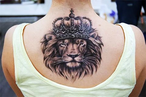 Tatuagem de um leão com uma coroa nas costas da rapariga