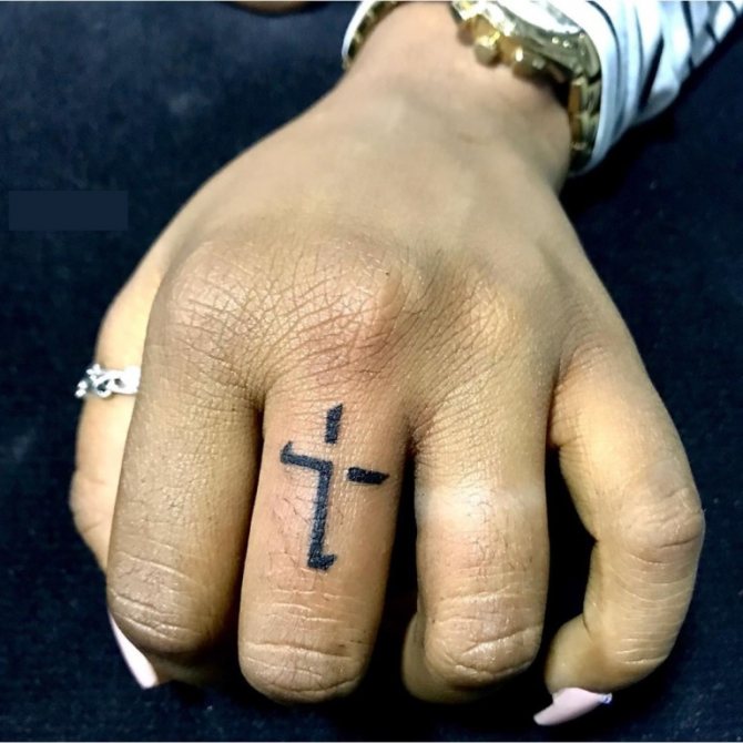 σταυρός στο τατουάζ του αντίχειρα που σημαίνει στη ζώνη