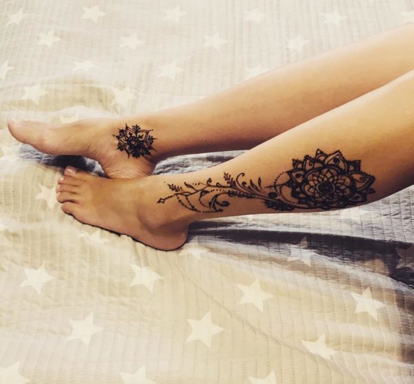 Mehendi om und Blumen auf ihrem Bein