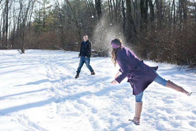 Bărbat și femeie joacă bulgăre de zăpadă
