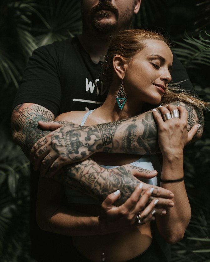 Άνθρωπος τατουάζ χέρια αγκαλιάζει γυναίκα