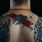 muž so slovanským tetovaním na chrbte