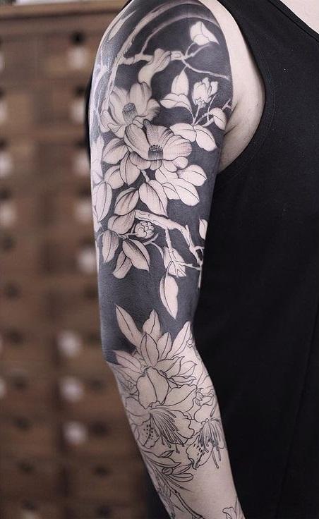 Mænds tatovering på arm med sort arbejde og blomster