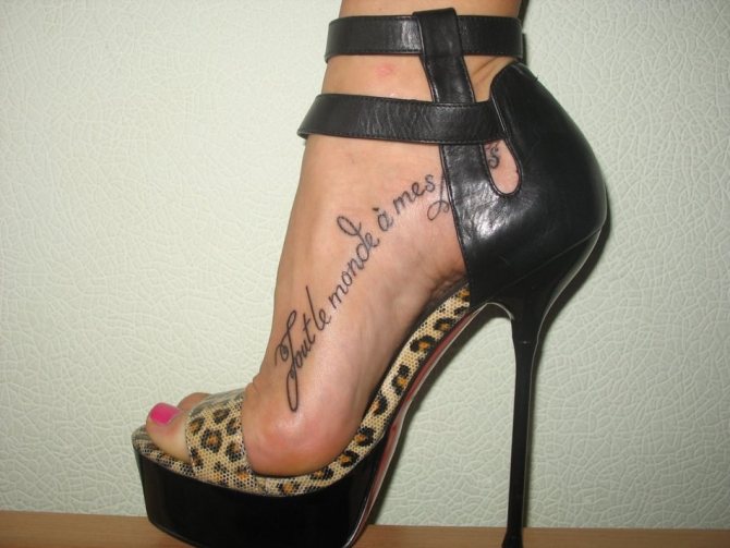 Le iscrizioni del tatuaggio lungo il piede sembrano grandiose in combinazione con le scarpe con il tacco alto.