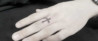 Kors tatovering på tommelfinger
