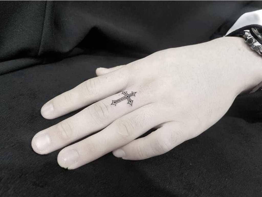 Kors tatovering på fingeren