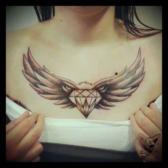 Tatuaj cu un diamant și aripi deasupra pieptului