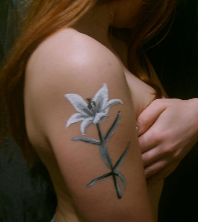 女性の肩にある百合の花のタトゥー