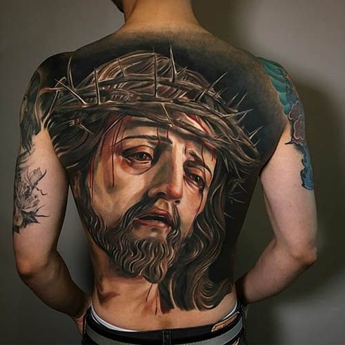 腕、背中、肩、胸にイエスのタトゥー。意味は、十字架の上で、悪魔と、機械と、鳩と