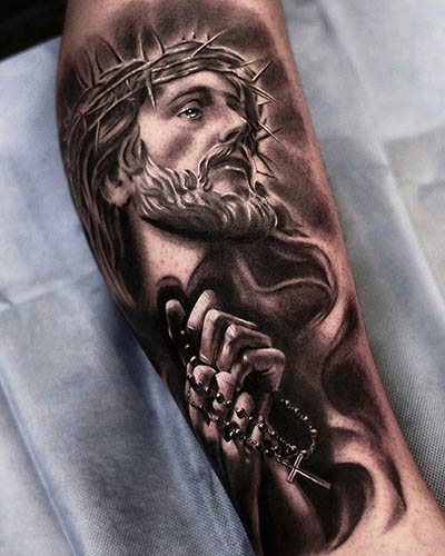 腕、背中、肩、胸にイエスのタトゥー。意味：十字架の上で、悪魔と、機関銃と、鳩と