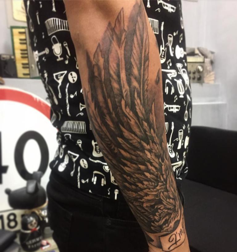 Tetovējuma spārni cieši pieguļ vīrieša apakšdelmam