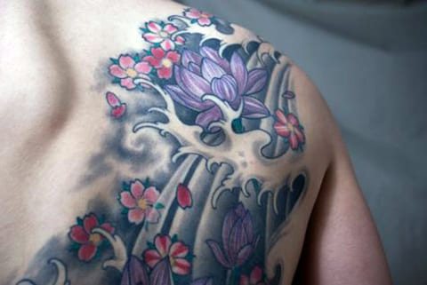 Tattoo waterlelie op zijn schouderblad
