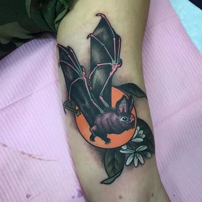 vleermuis tattoo met bloemen op biceps