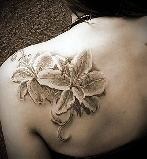 Tätowierung einer Lilie auf dem Schulterblatt eines Mädchens - Foto