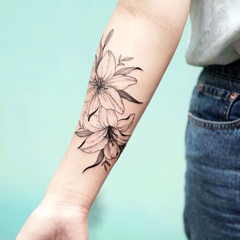 Tätowierung einer Lilie auf dem Arm eines Mädchens - Foto