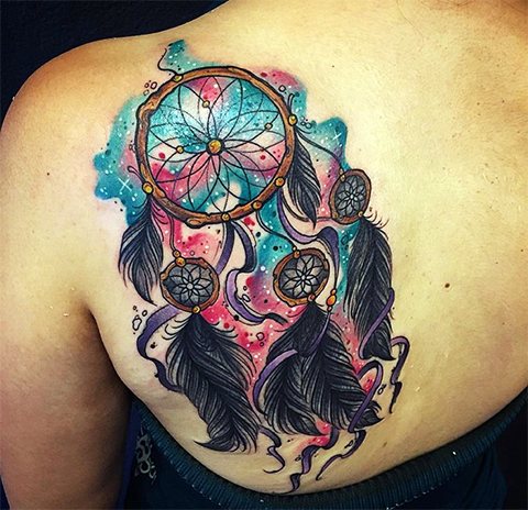 Apanhador de sonhos de tatuagem na omoplata de uma rapariga
