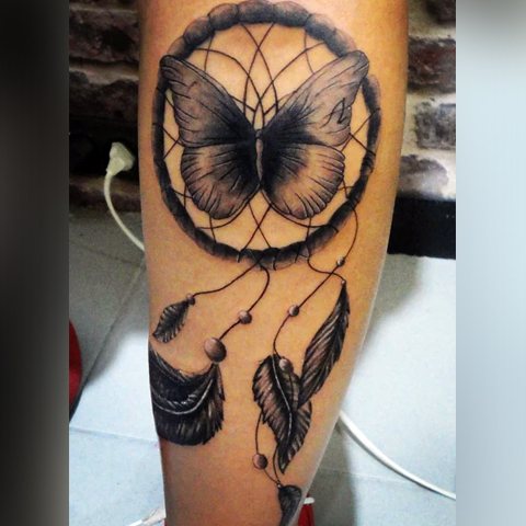 Tatouage d'un attrape-rêves avec un papillon à l'intérieur