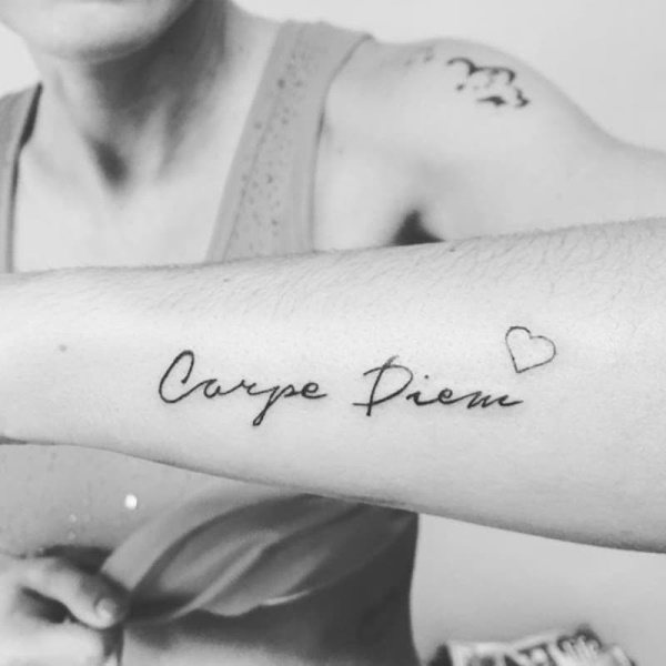 Tatuagem apreende o momento em latim (carpe diem). Esboço, fotografia, significado