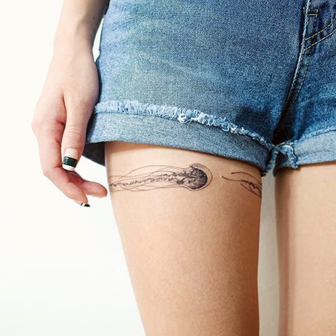 Tatuaggio di una medusa sulla coscia di una ragazza