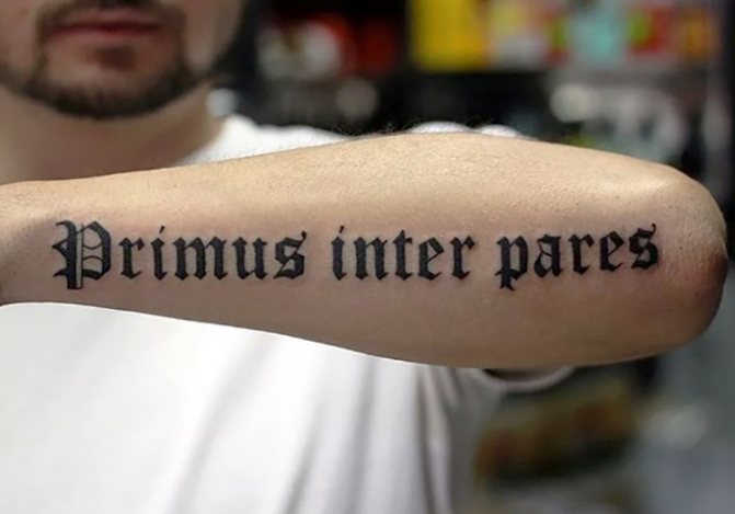 Tatuering på en mans arm med en mening, mening, inskriptioner med översättning slaviska, latinska, keltiska mönster