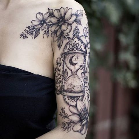Smėlio laikrodžio ir gėlių tatuiruotė ant merginos rankos