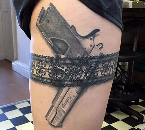 Татуировка пистолет на бедрото в жартиера на момиче