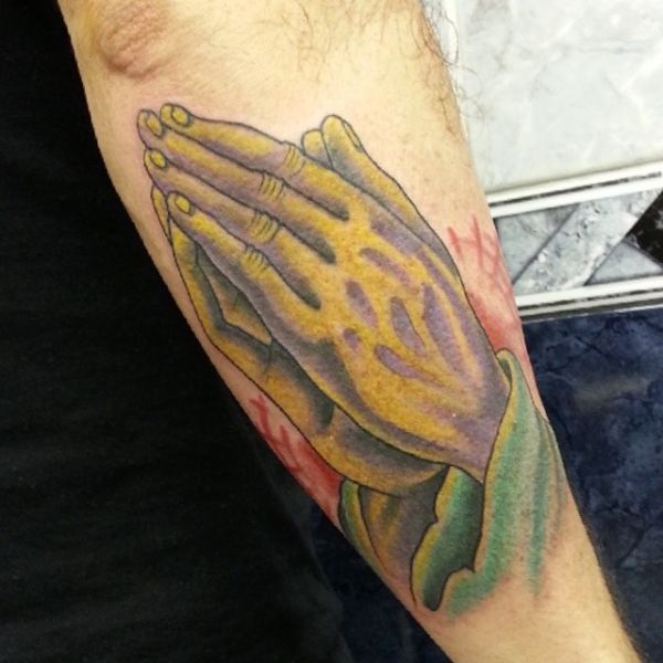 Tatoeage van biddende handen op onderarm