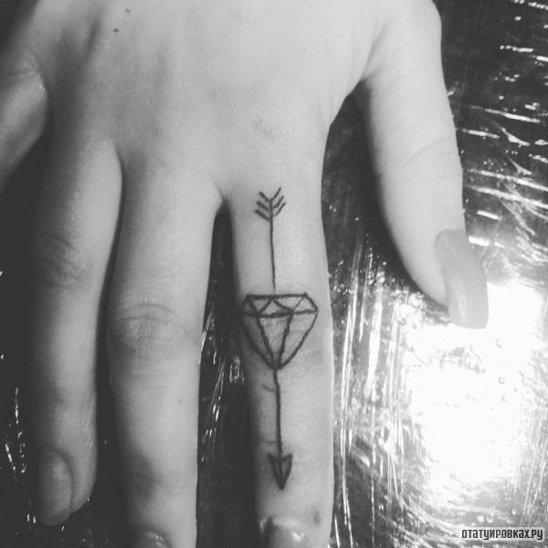 freccia tatuaggio con diamante sul dito
