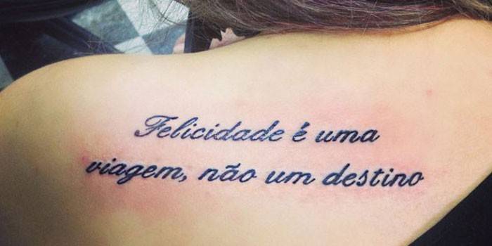 Tatuaggio sulla schiena di una ragazza: la felicità è un viaggio, non una destinazione