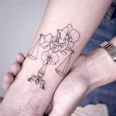 Egy Mérleg tetoválása virágokkal kombinálva