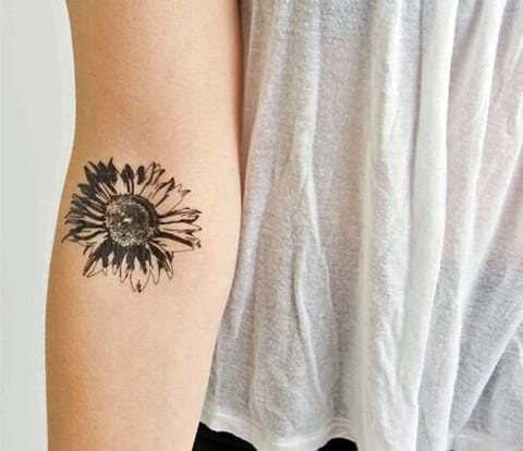 Tatoeage op de arm van een meisje met een madeliefje