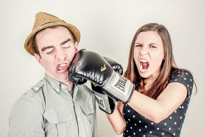 Kvinde slår mand med hånden, mens hun har en boksehandske på